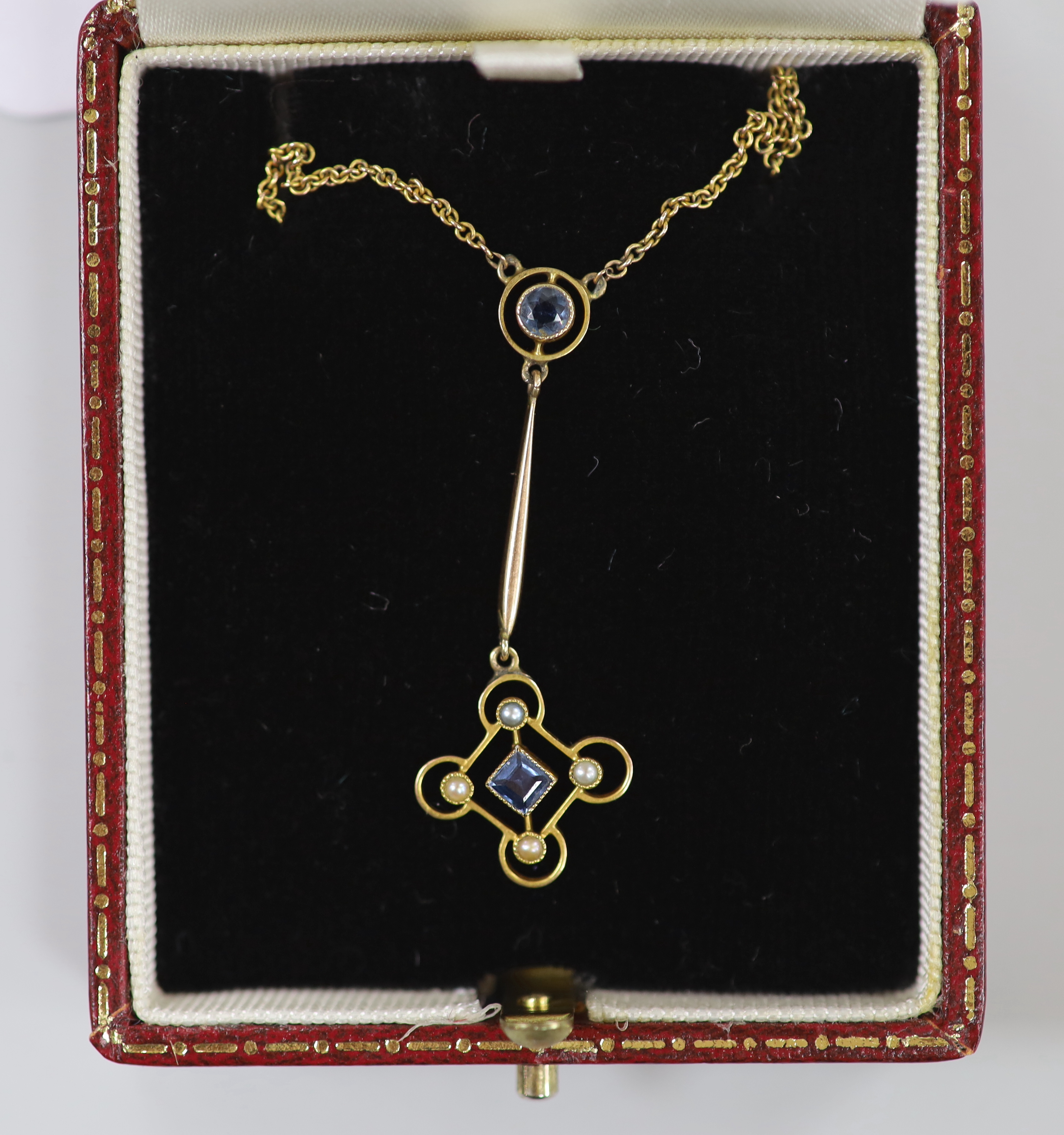 An Edwardian yellow metal, sapphire? and seed pearl set drop pendant necklace, pendant 43mm, chain 43cm, gross weight 3.4 grams.